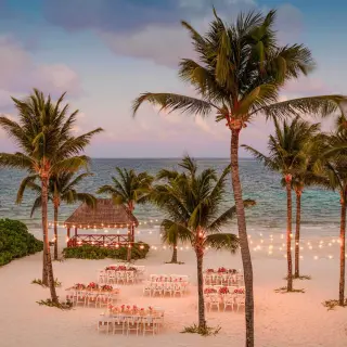 Beachfront wedding reception with string lights and palm trees at Excellence Riviera Cancun, Riviera Maya