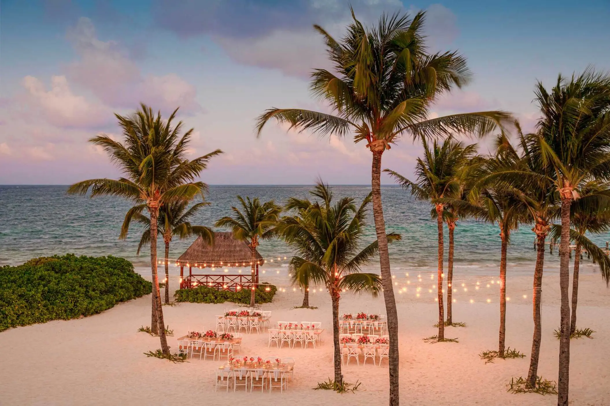 Beachfront wedding reception with string lights and palm trees at Excellence Riviera Cancun, Riviera Maya