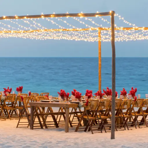 Beachfront wedding reception with string lights and red florals at Finest Playa Mujeres, Cancun