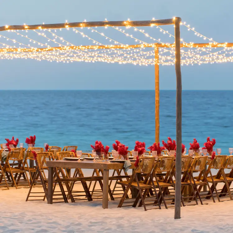 Beachfront wedding reception with string lights and red florals at Finest Playa Mujeres, Cancun