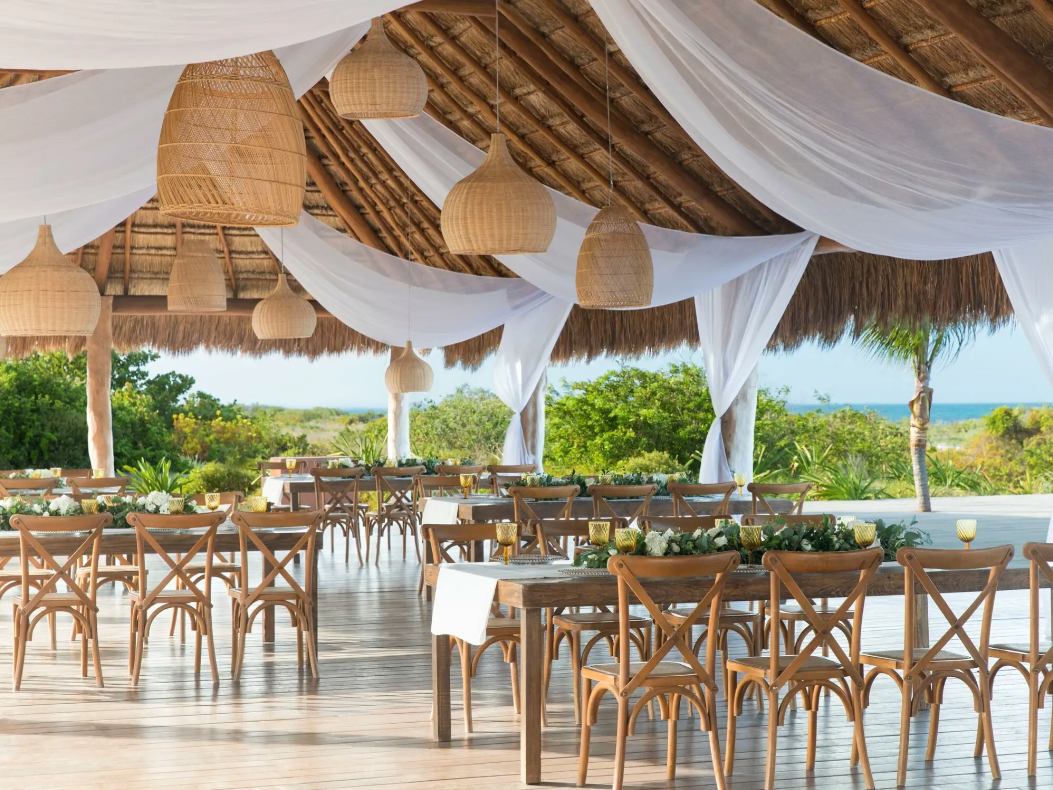 Wedding reception under a palapa with white drapery and wicker lanterns at Finest Playa Mujeres, Cancun