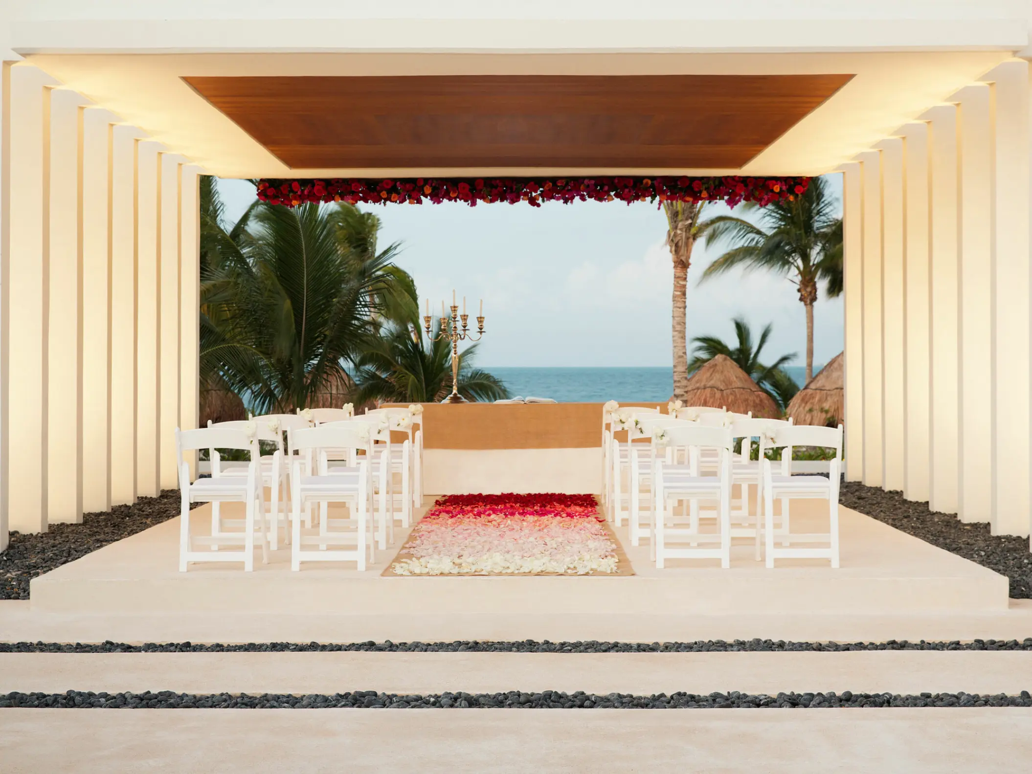 Stone gazebo wedding ceremony with white chairs and floral aisle at Finest Playa Mujeres, Cancun