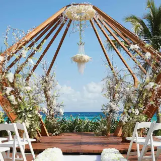 Geometric wooden gazebo wedding ceremony with white flowers at The Fives Beach, Playa Del Carmen