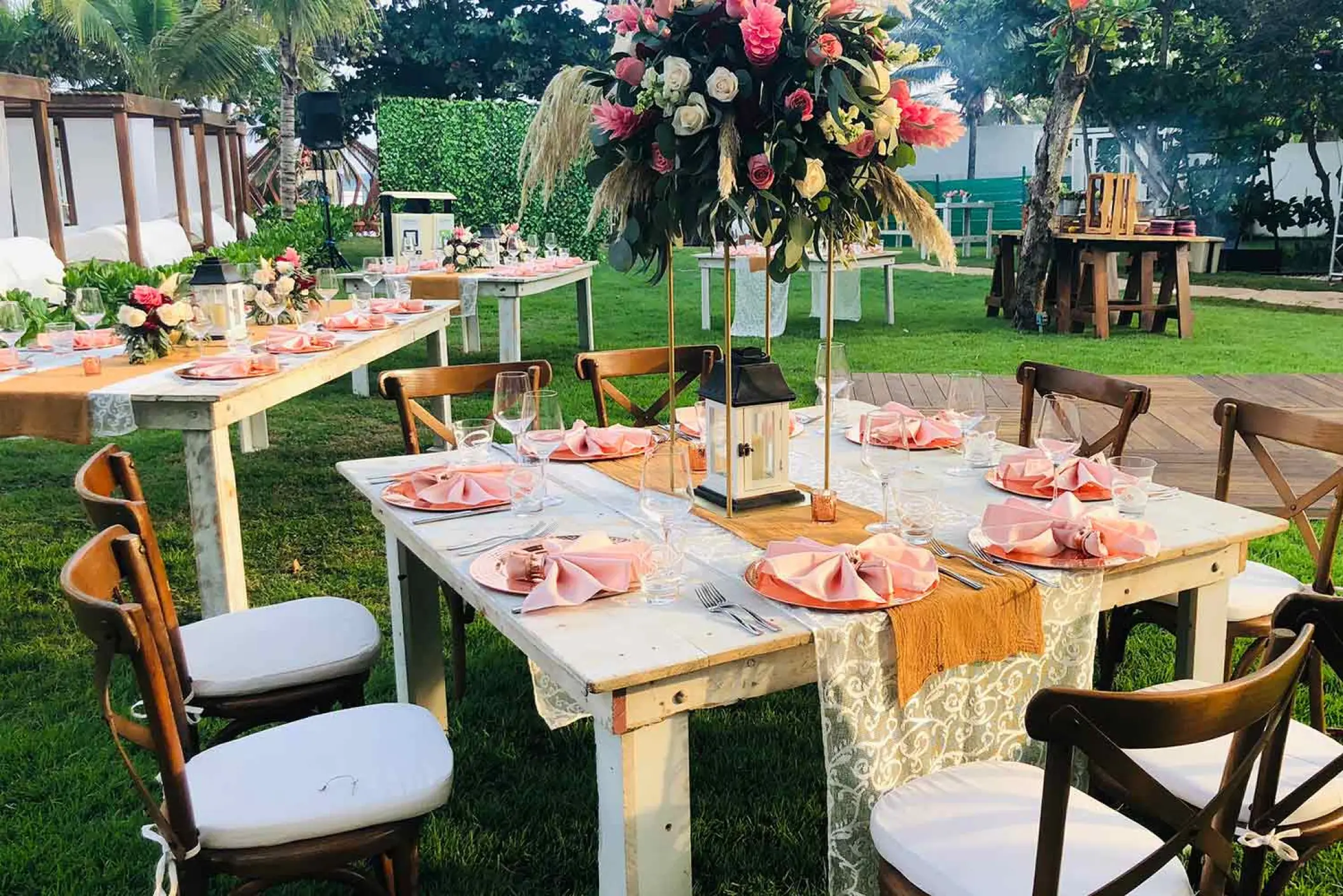 Garden wedding reception with pink floral centerpieces and wooden tables at The Fives Beach Hotel, Playa Del Carmen
