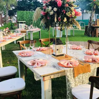 Garden wedding reception with pink floral centerpieces and wooden tables at The Fives Beach Hotel, Playa Del Carmen