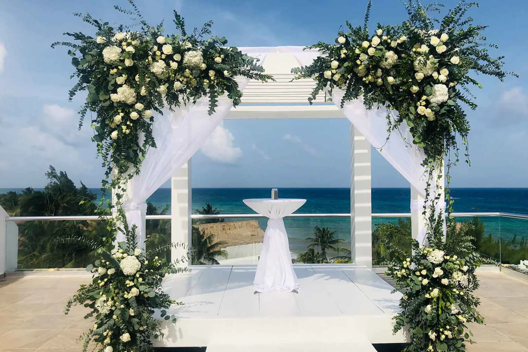Sky deck wedding ceremony setup with white floral arch at The Fives Beach Hotel, Playa Del Carmen