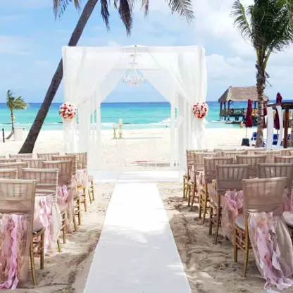 Beachfront wedding ceremony setup with white huppah and pink ruffled chairs at The Fives Beach Hotel, Playa Del Carmen