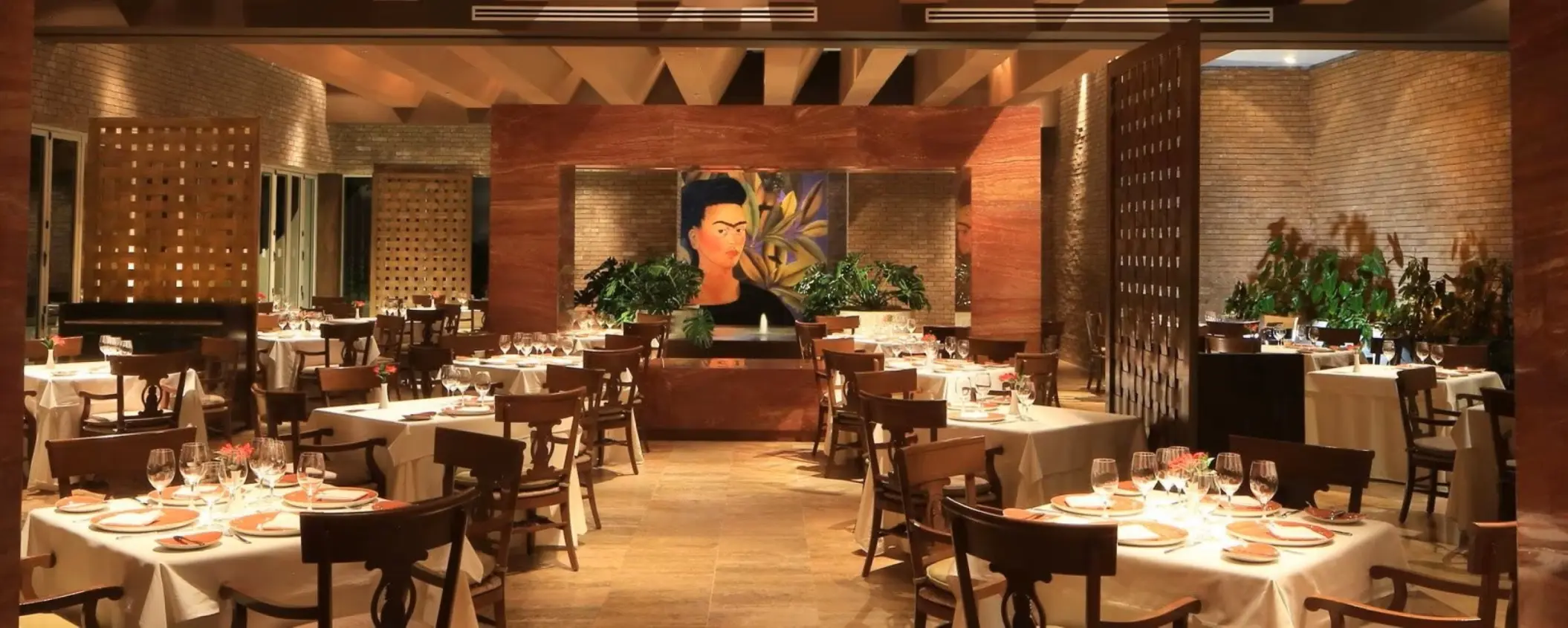 Frida restaurant interior with white tablecloths and dark wood chairs at Grand Velas Riviera Maya