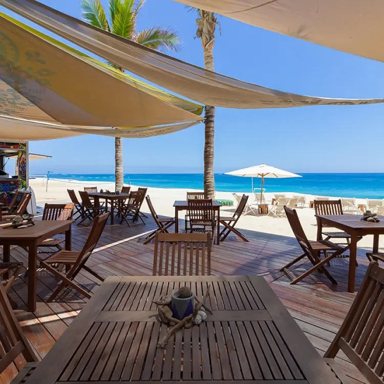 Outdoor beach bar and dining area with shaded wooden tables at Garza Blanca Los Cabos, Cabo San Lucas
