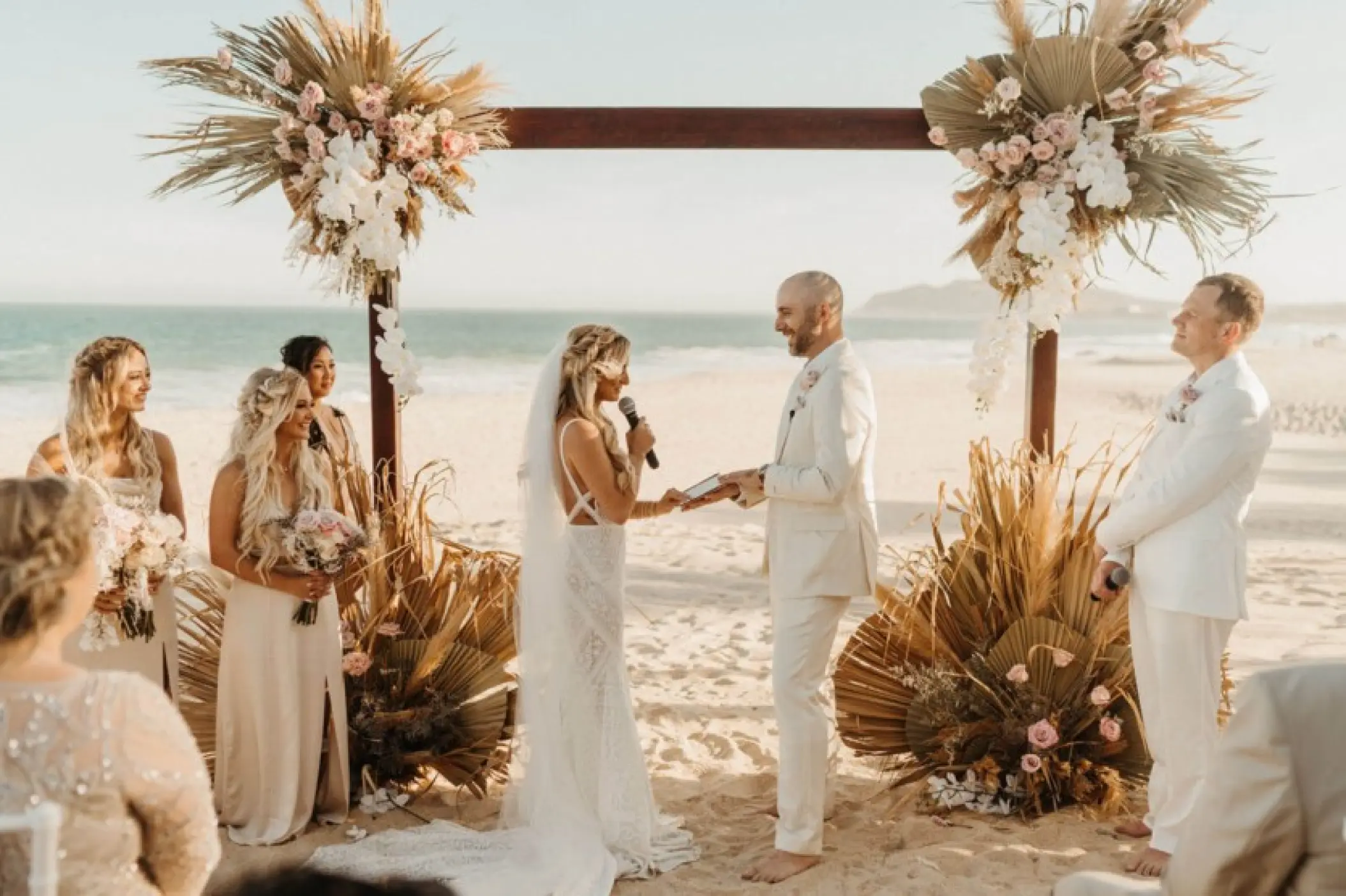 Beachfront wedding ceremony with dried palm decor at Garza Blanca Los Cabos, Cabo San Lucas