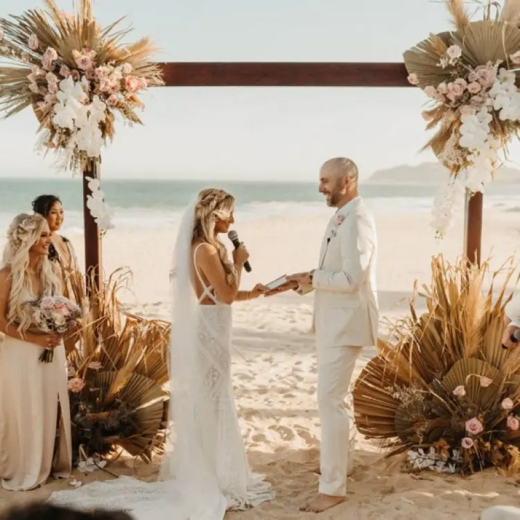 Beachfront wedding ceremony with dried palm decor at Garza Blanca Los Cabos, Cabo San Lucas