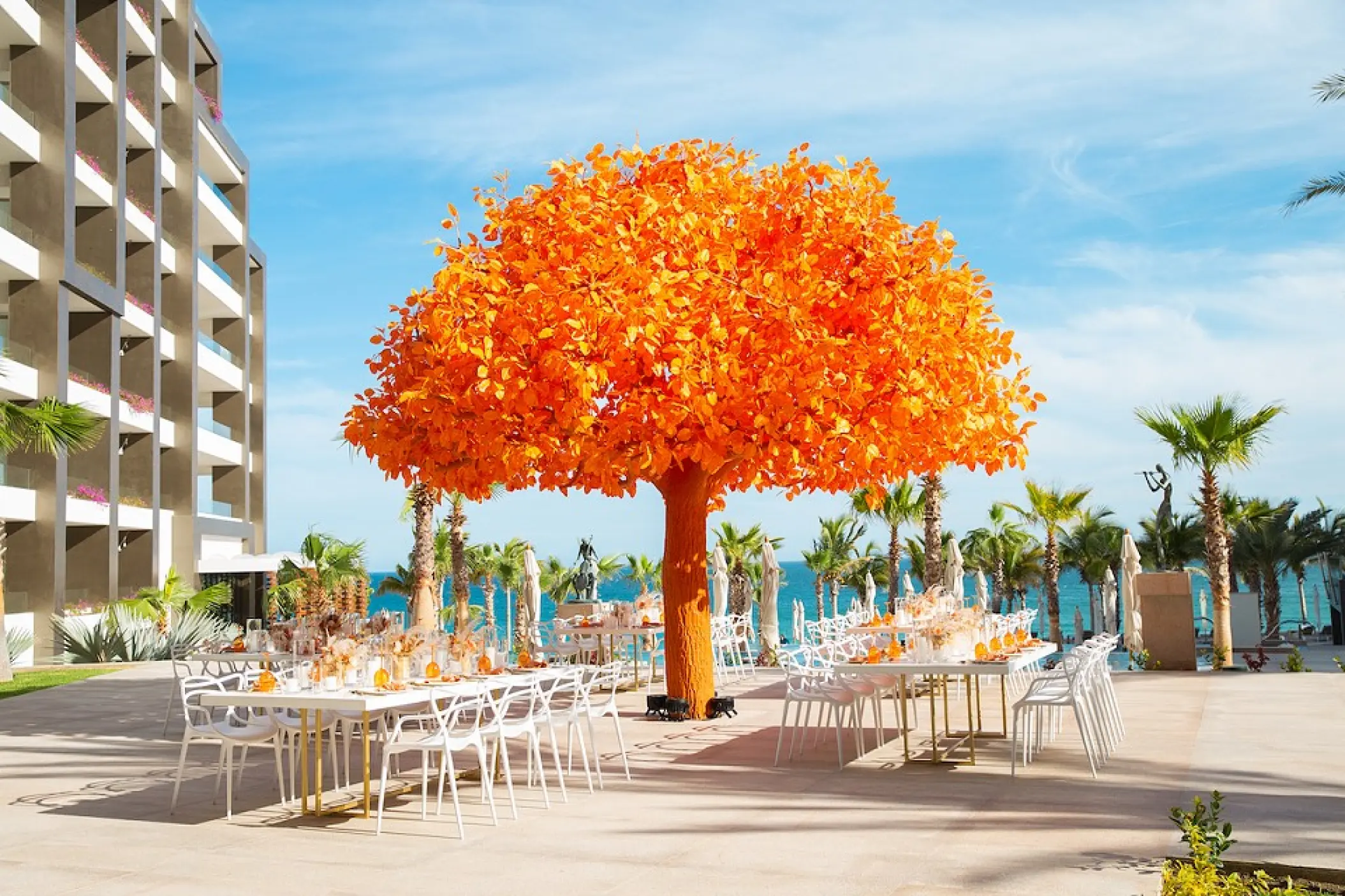 Outdoor wedding reception with a large orange tree sculpture at Garza Blanca Los Cabos, Cabo San Lucas