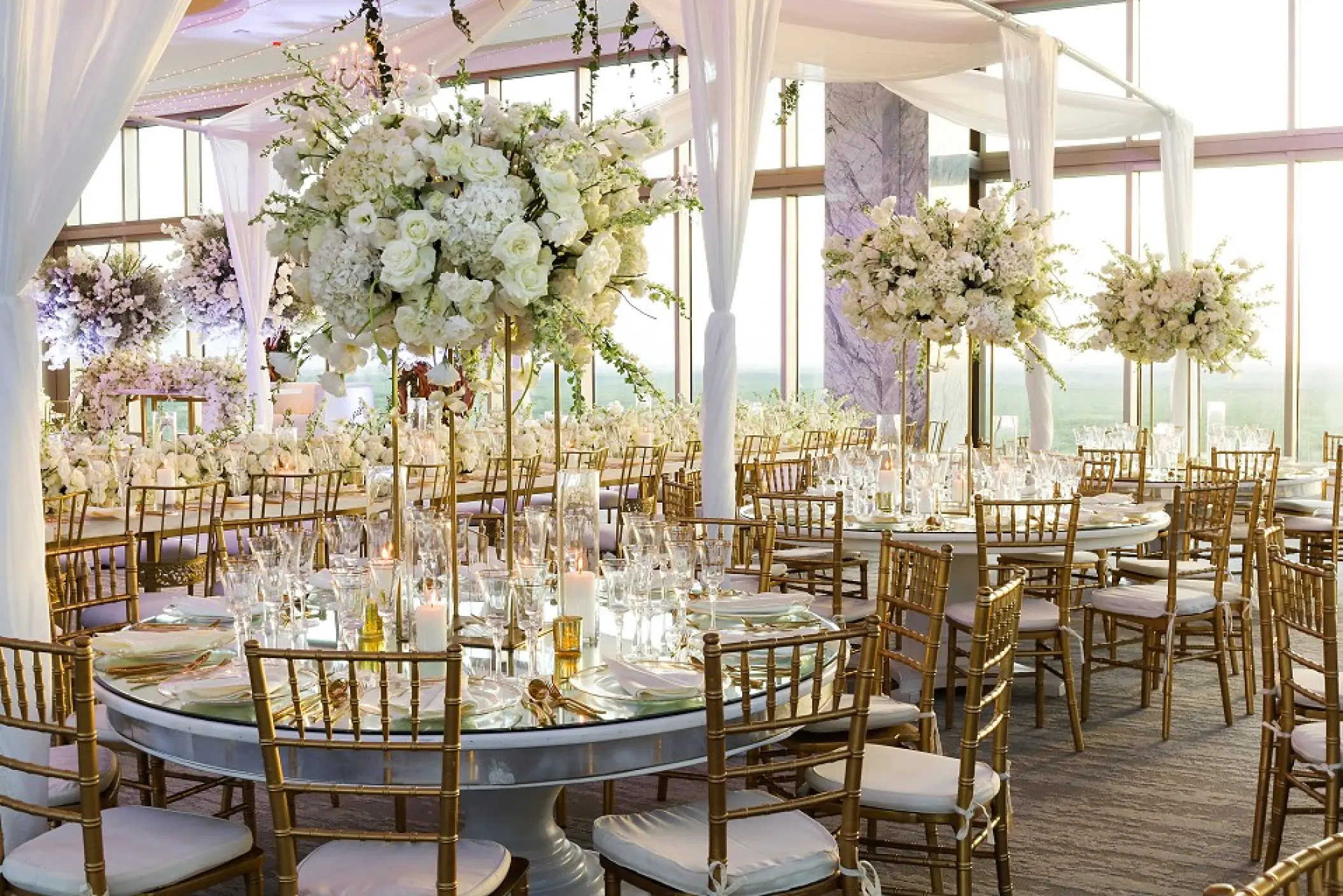 Sky Room wedding reception with white floral centerpieces and gold chairs at Garza Blanca Cancun