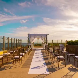 Rooftop wedding ceremony setup with white pergola and gold chairs at Generations Riviera Maya