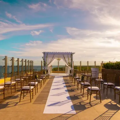 Rooftop wedding ceremony setup with white pergola and gold chairs at Generations Riviera Maya