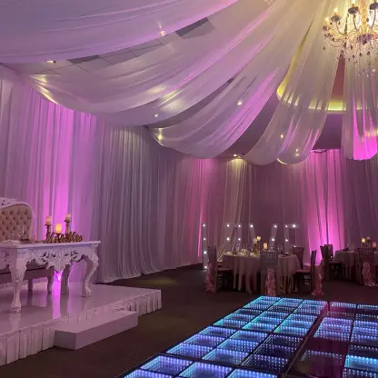 Indoor ballroom wedding reception with a lighted dance floor and draped ceiling at Generations Riviera Maya