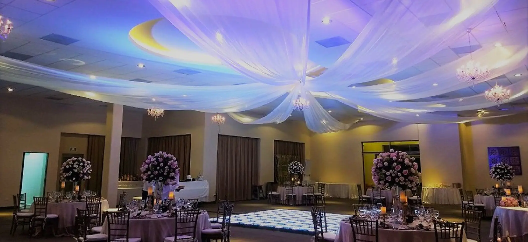 Indoor wedding reception with white ceiling draping and floral centerpieces at Generations Riviera Maya, Riviera Maya