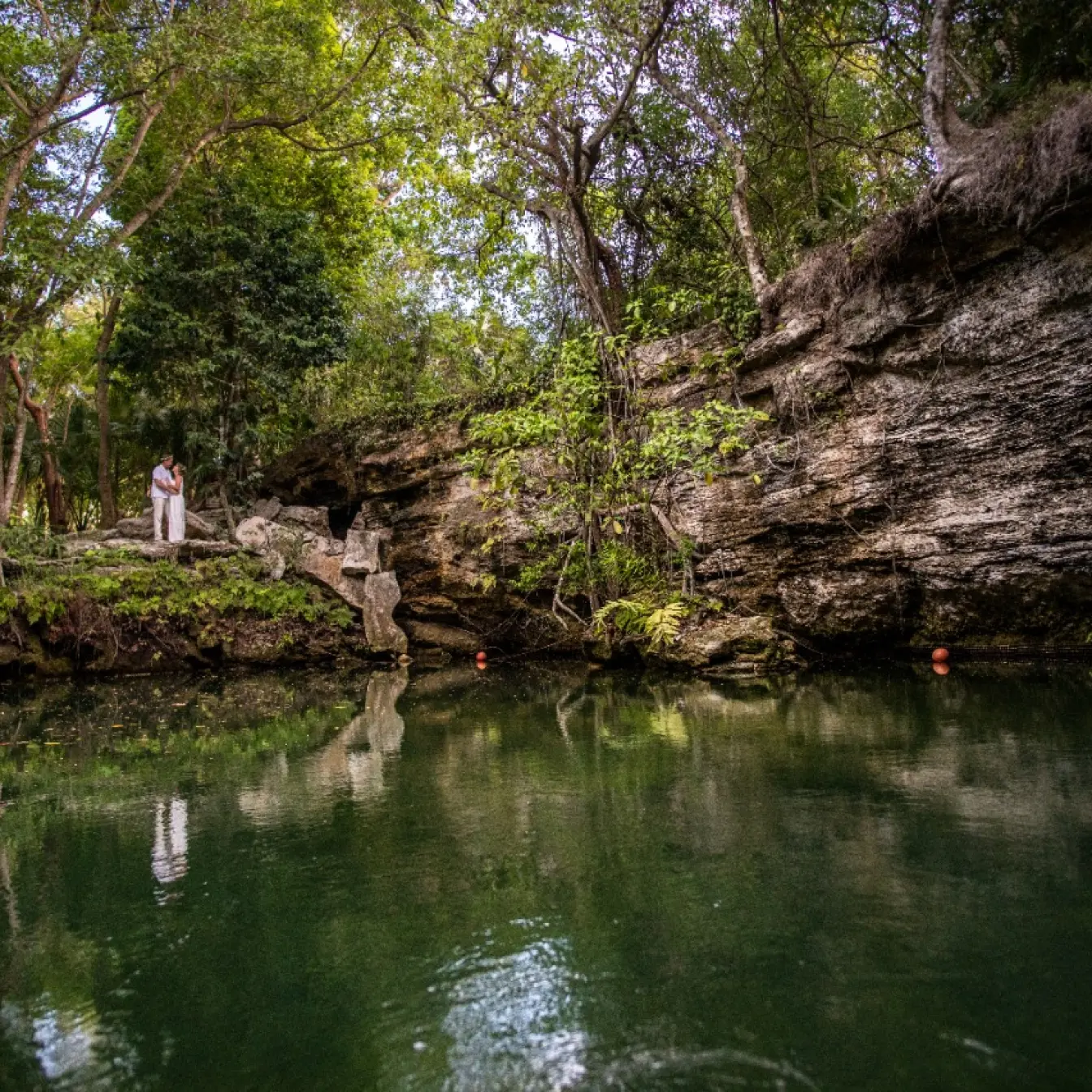 The bride and groom standing by a cenote at Generations Riviera Maya