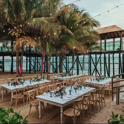 Beachfront wedding reception tables under palm trees and string lights at Generations Riviera Maya