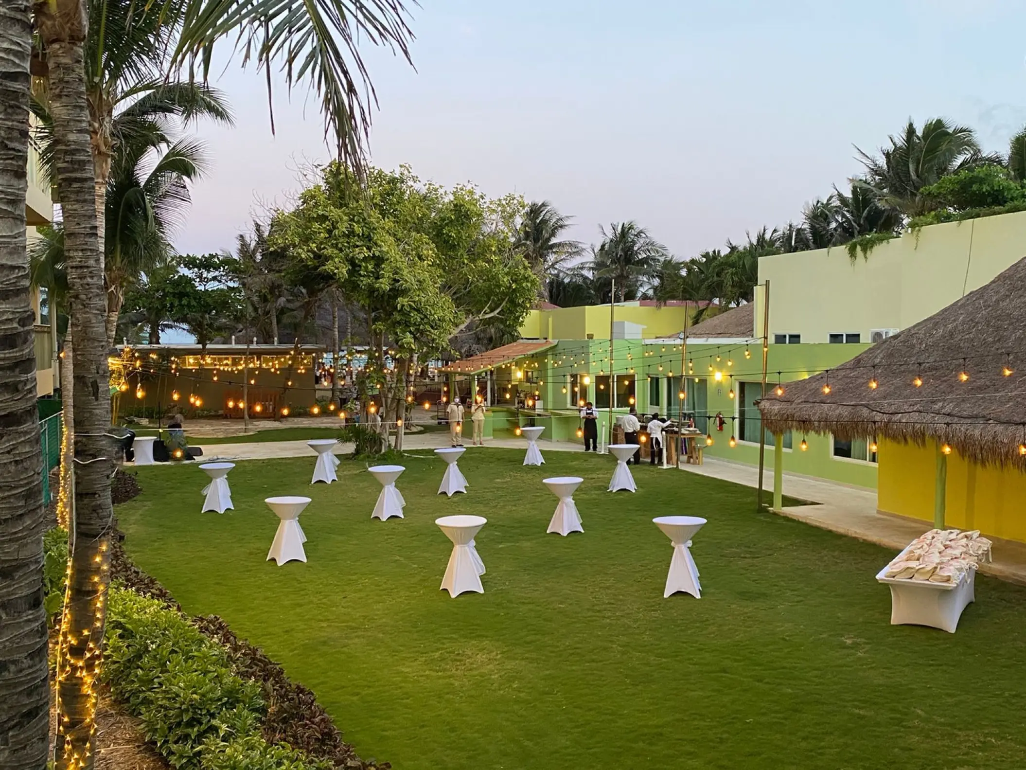 Cocktail hour garden setup with string lights and high-top tables at Generations Riviera Maya