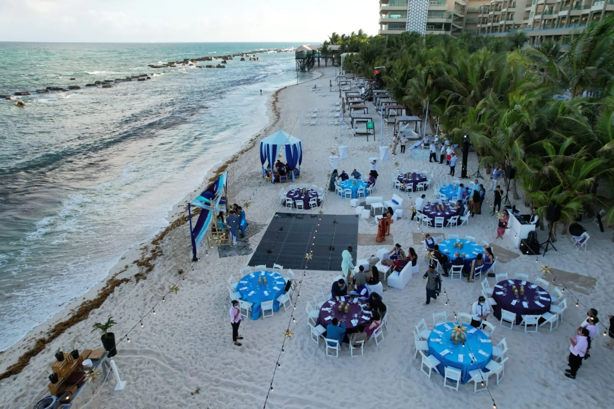 Beachfront wedding reception setup with blue and purple tables at Generations Riviera Maya