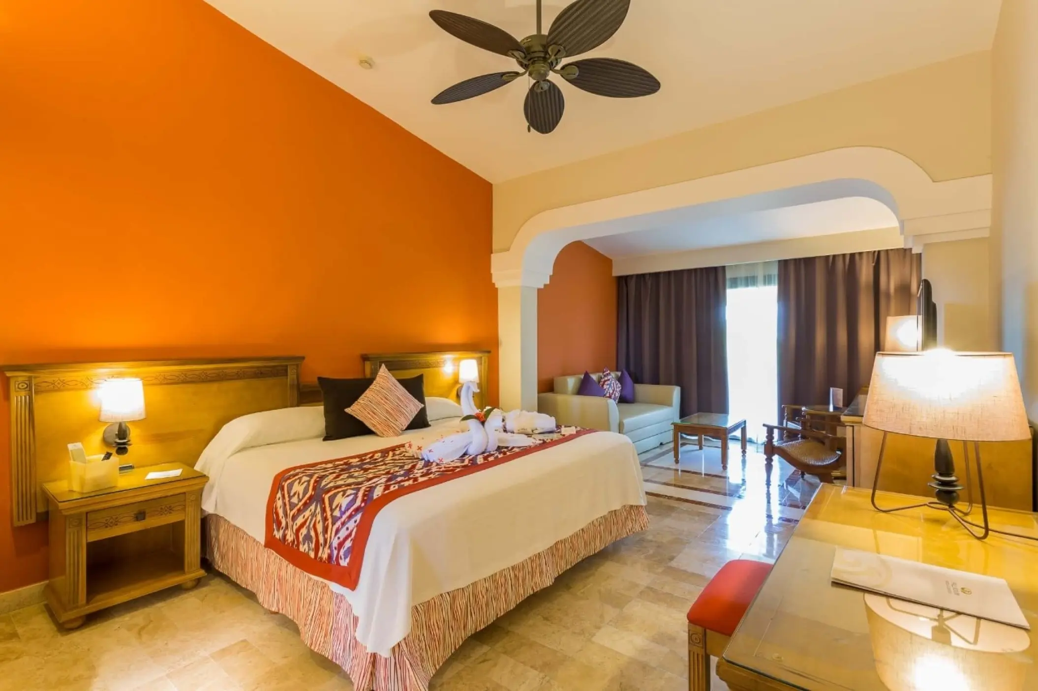 Guest suite with orange accent wall and sitting area at Grand Palladium Colonial, Riviera Maya
