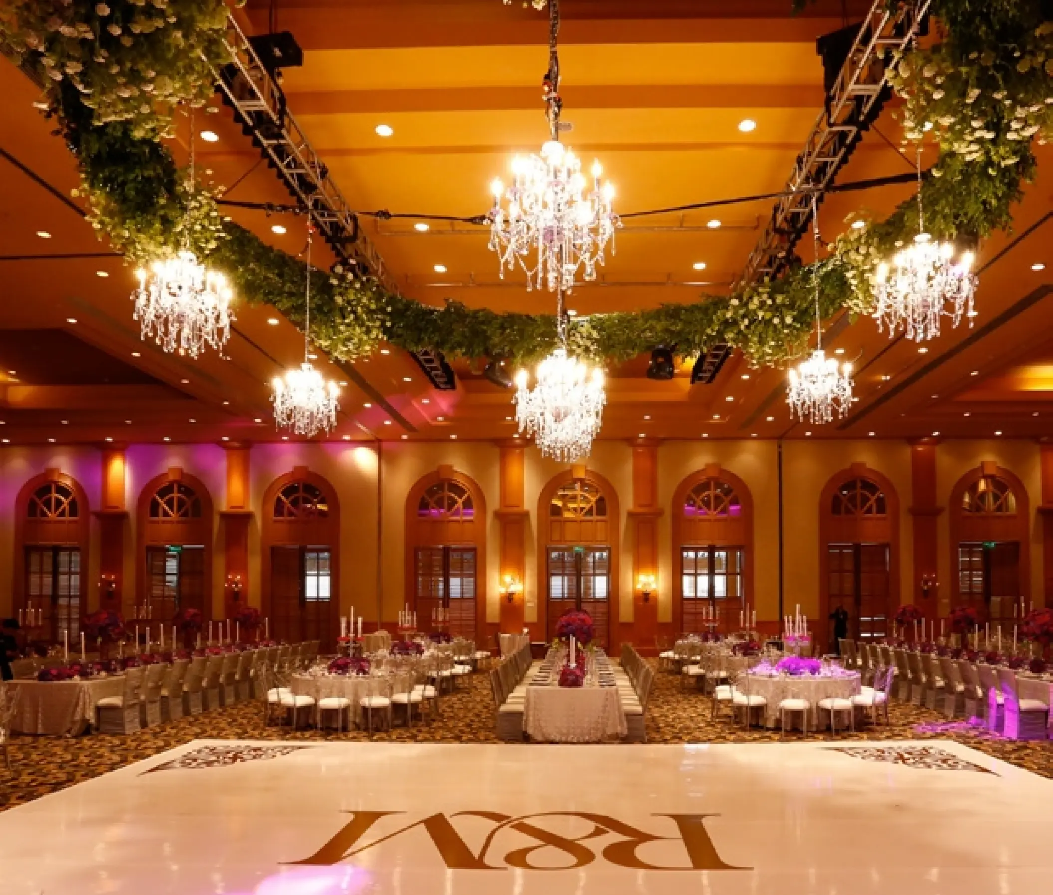 Indoor ballroom wedding reception with crystal chandeliers and a monogrammed dance floor at Grand Fiesta Americana Los Cabos