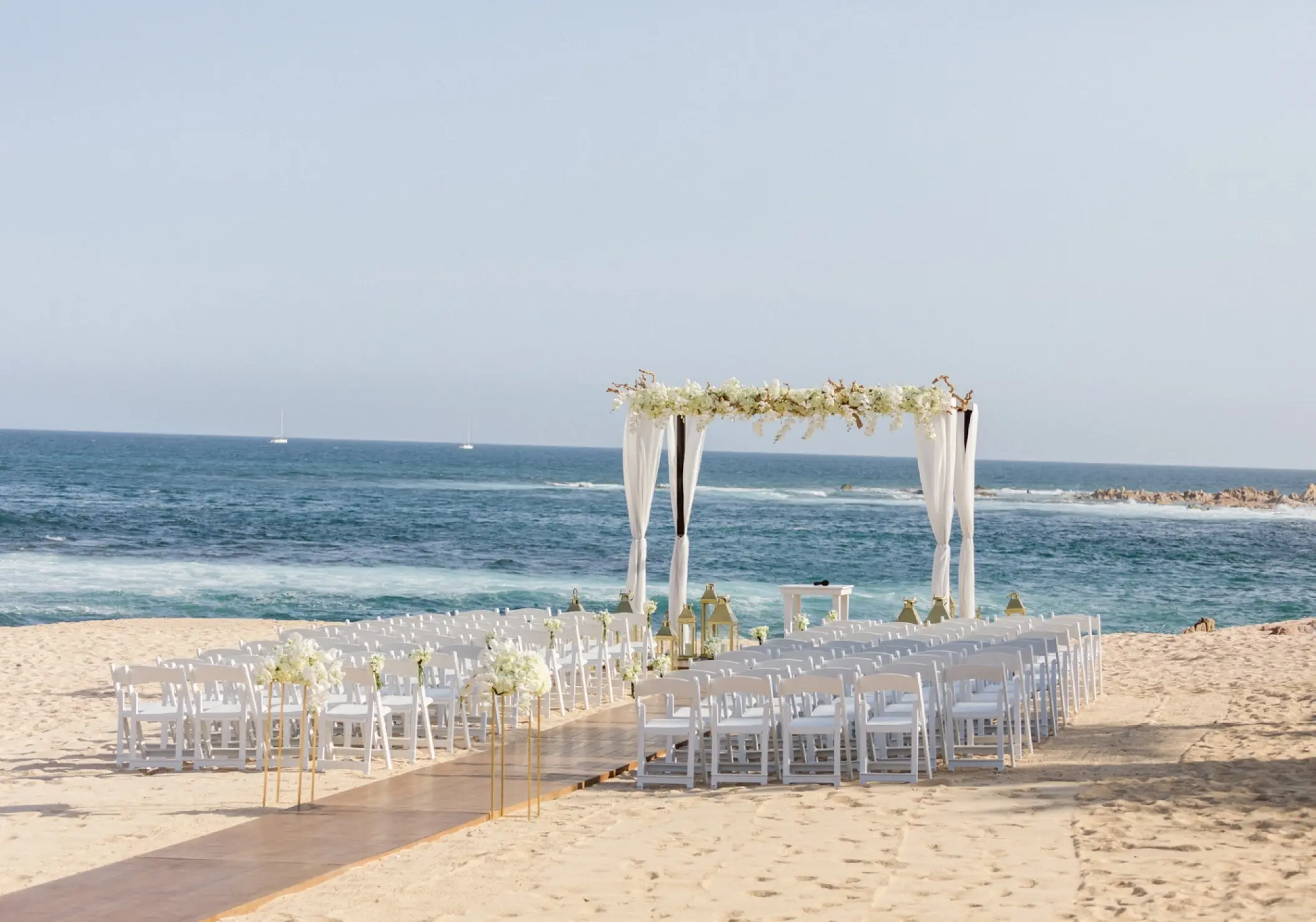 Beachfront wedding ceremony with white floral arch at Grand Fiesta Americana, Cabo San Lucas