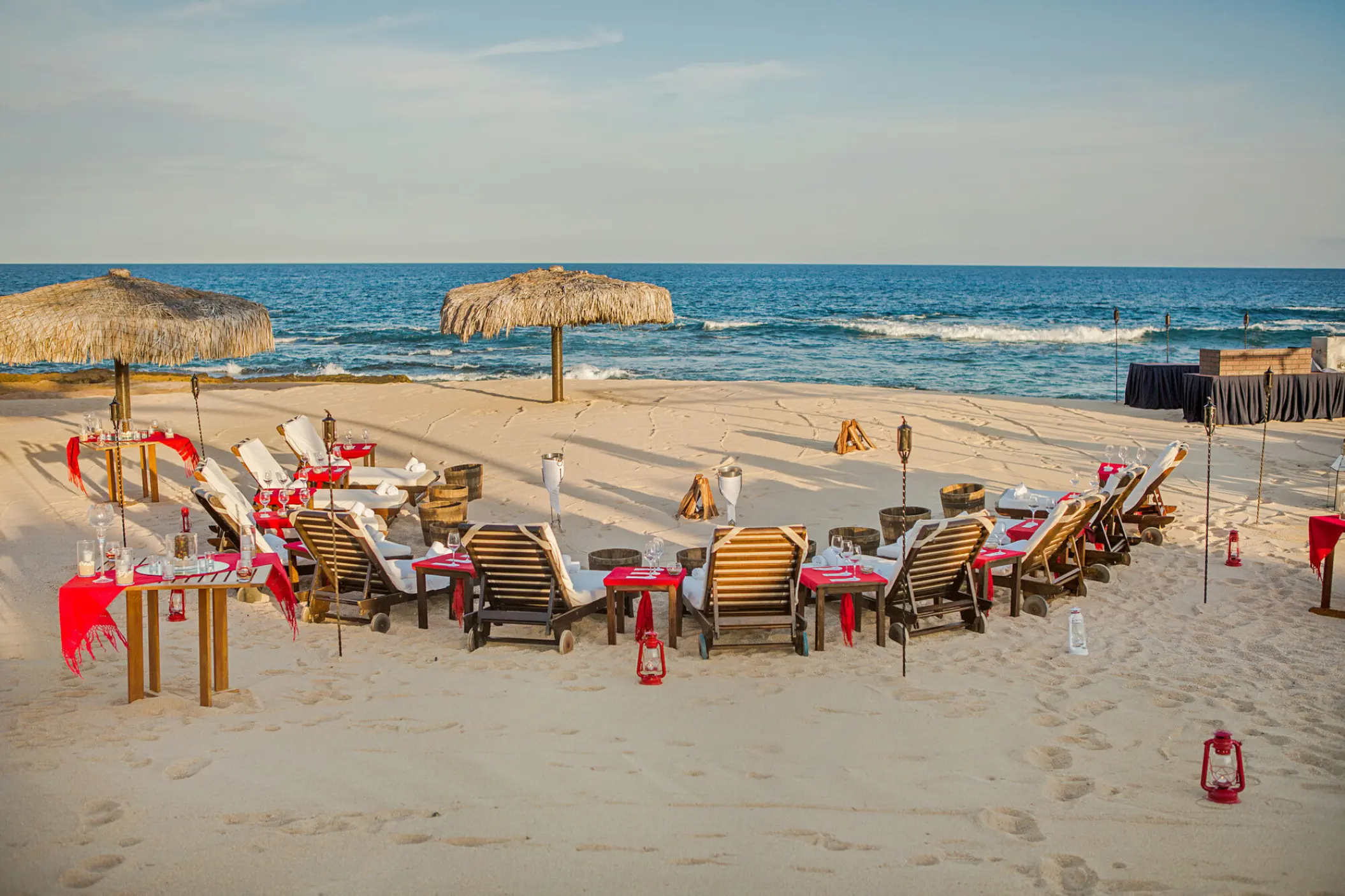 Beachfront wedding cocktail party setup with lounge chairs and red accents at Grand Fiesta Americana, Cabo San Lucas