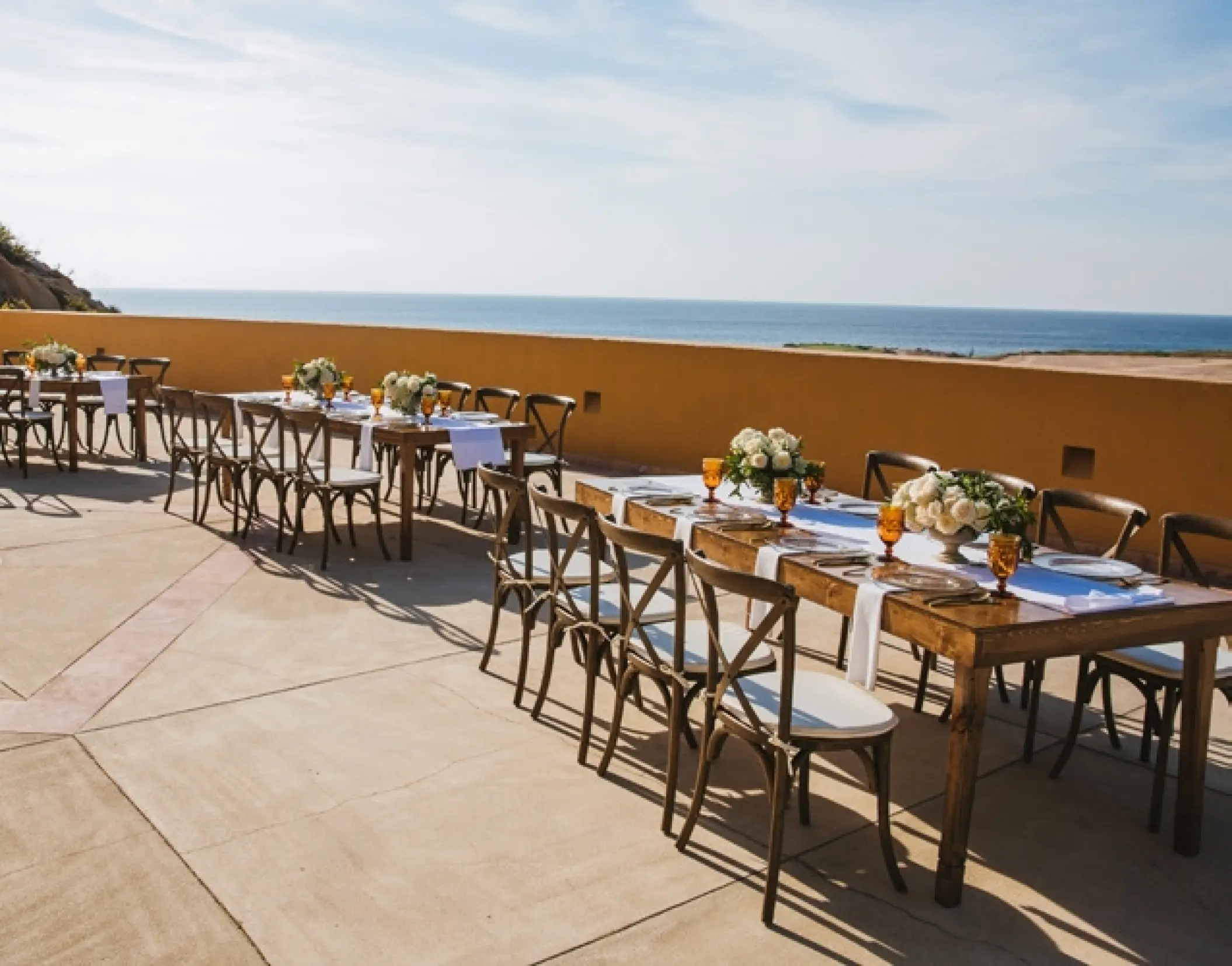 Oceanfront wedding reception with wooden farm tables at Grand Fiesta Americana Los Cabos, Cabo San Lucas