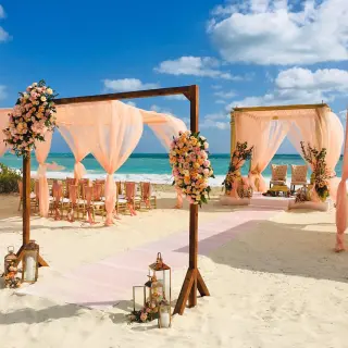 Beach wedding ceremony with peach fabric and floral arch at Grand Palladium Costa Mujeres, Cancun