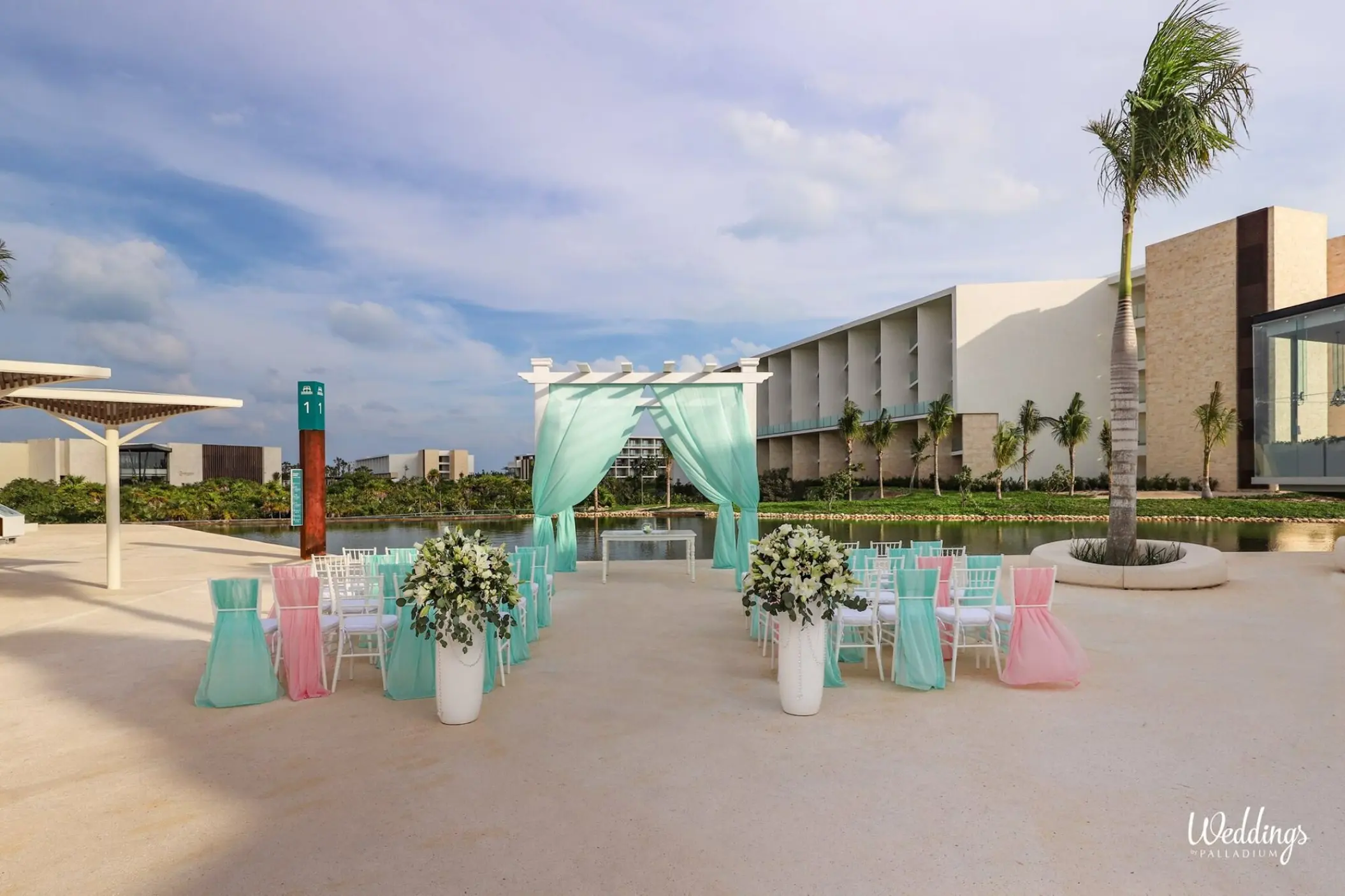 Outdoor wedding ceremony setup with mint green drapery and floral pillars at Grand Palladium Costa Mujeres, Cancun