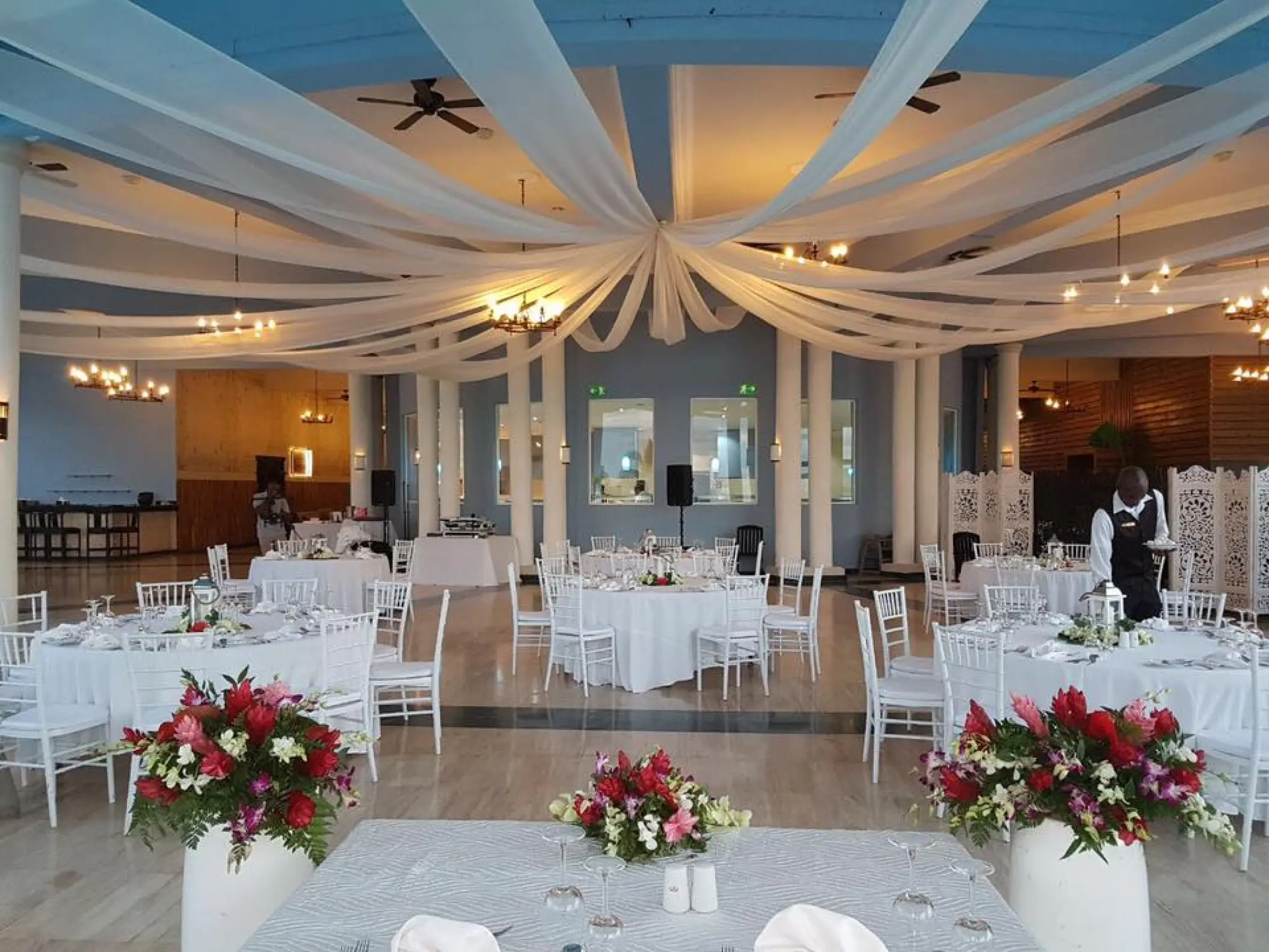 Indoor wedding reception with white ceiling draping and floral centerpieces at Grand Palladium Lady Hamilton, Ocho Rios