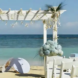 Beachfront wedding ceremony setup with white pergola and blue hydrangeas at Grand Palladium Jamaica, Ocho Rios