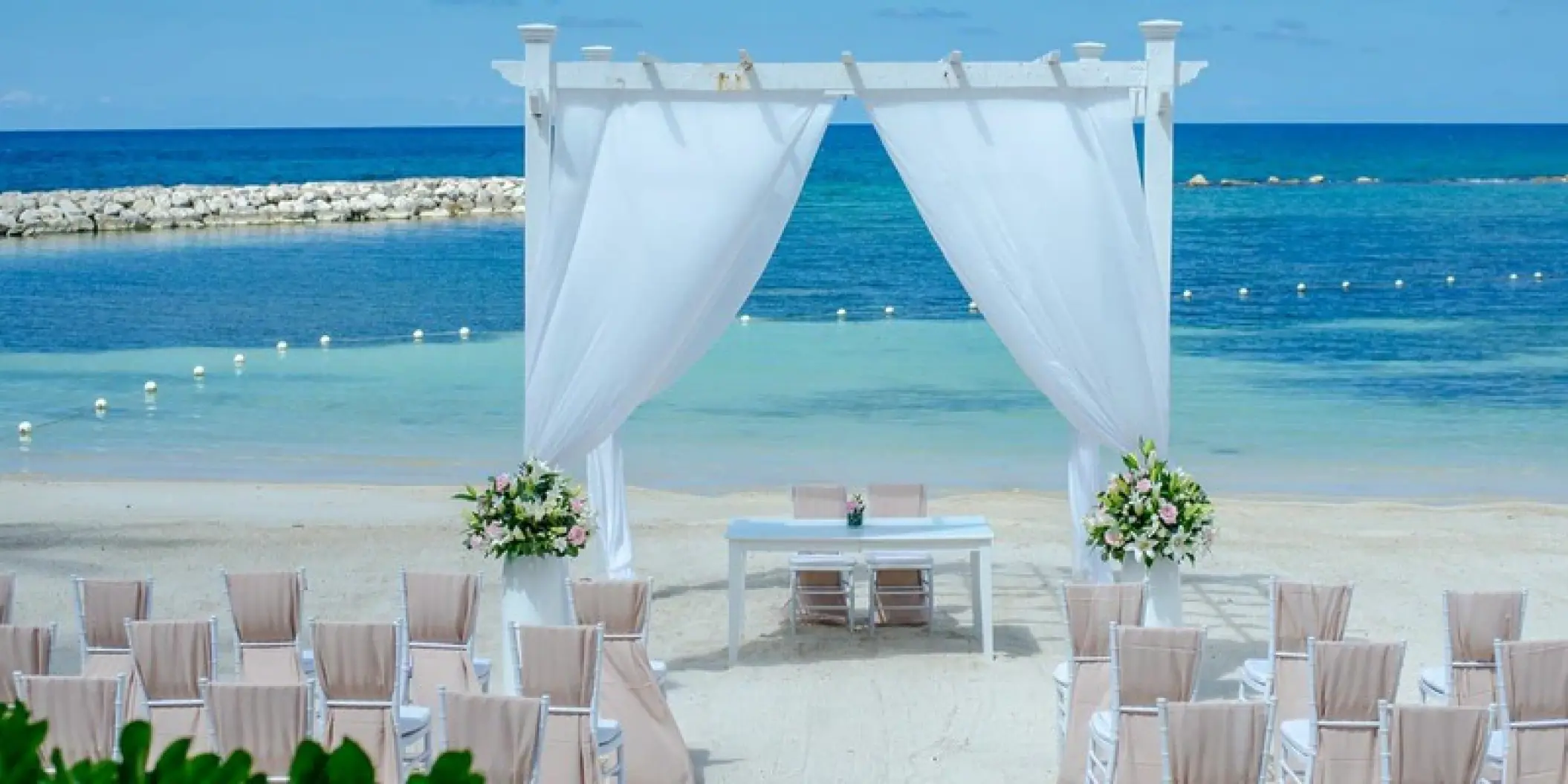 Beachfront wedding ceremony with a white pergola and draped fabric at Grand Palladium Jamaica, Ocho Rios