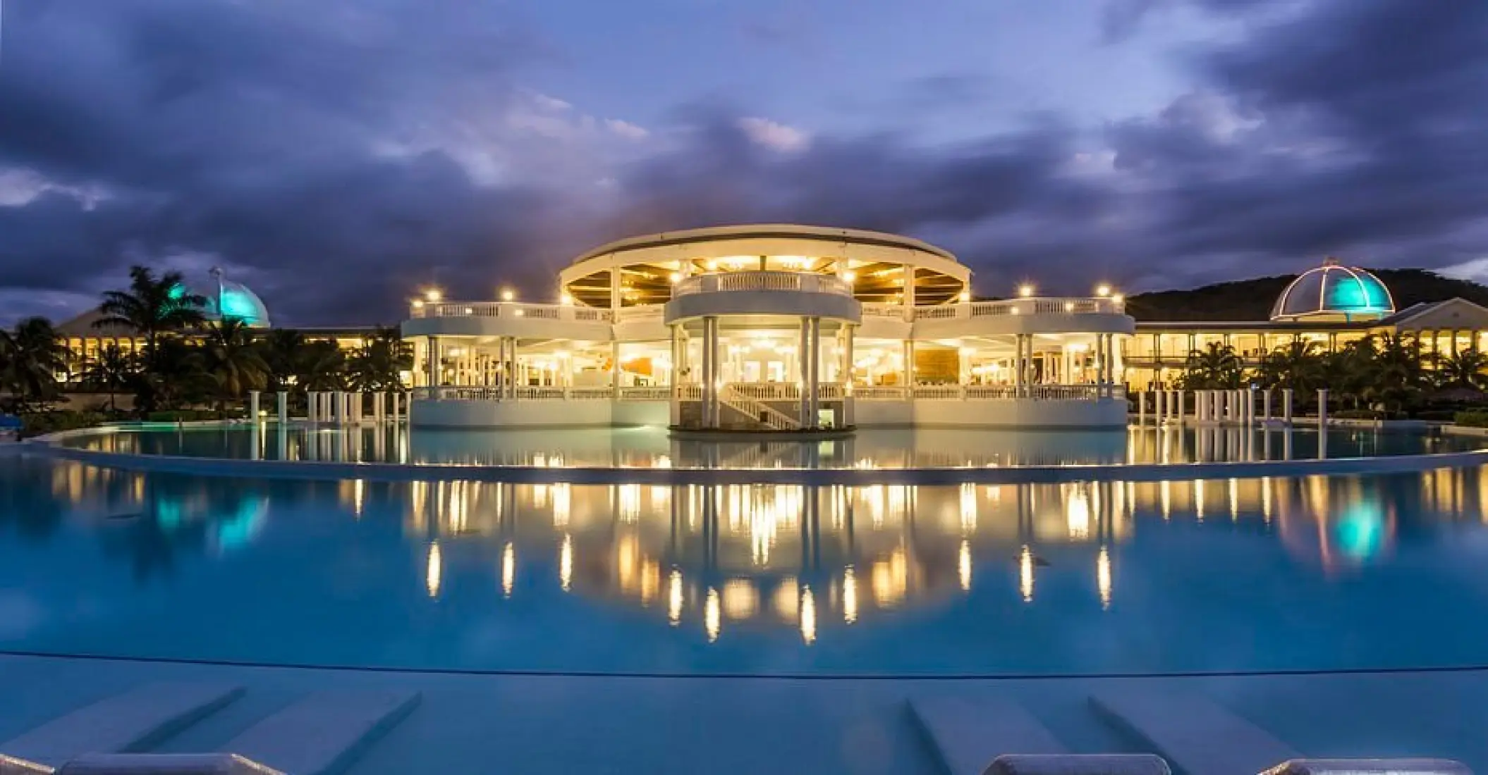 Grand Palladium Lady Hamilton infinity pool and lit resort facade at dusk, Ocho Rios