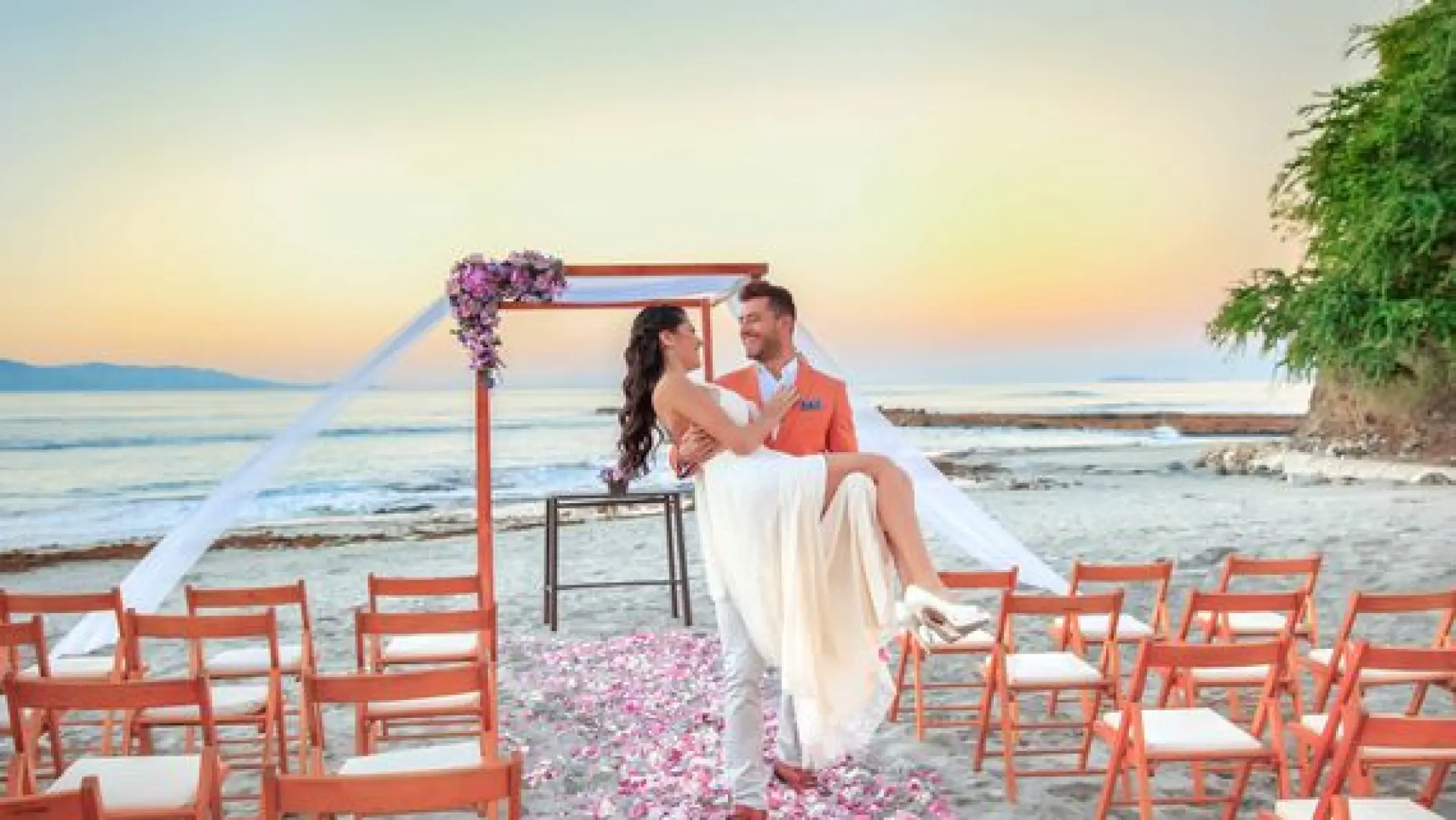 Groom carrying the bride at a beach ceremony at Grand Palladium Vallarta, Puerto Vallarta