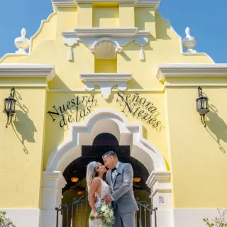 The bride and groom kissing in front of the yellow chapel at Grand Palladium Vallarta, Puerto Vallarta