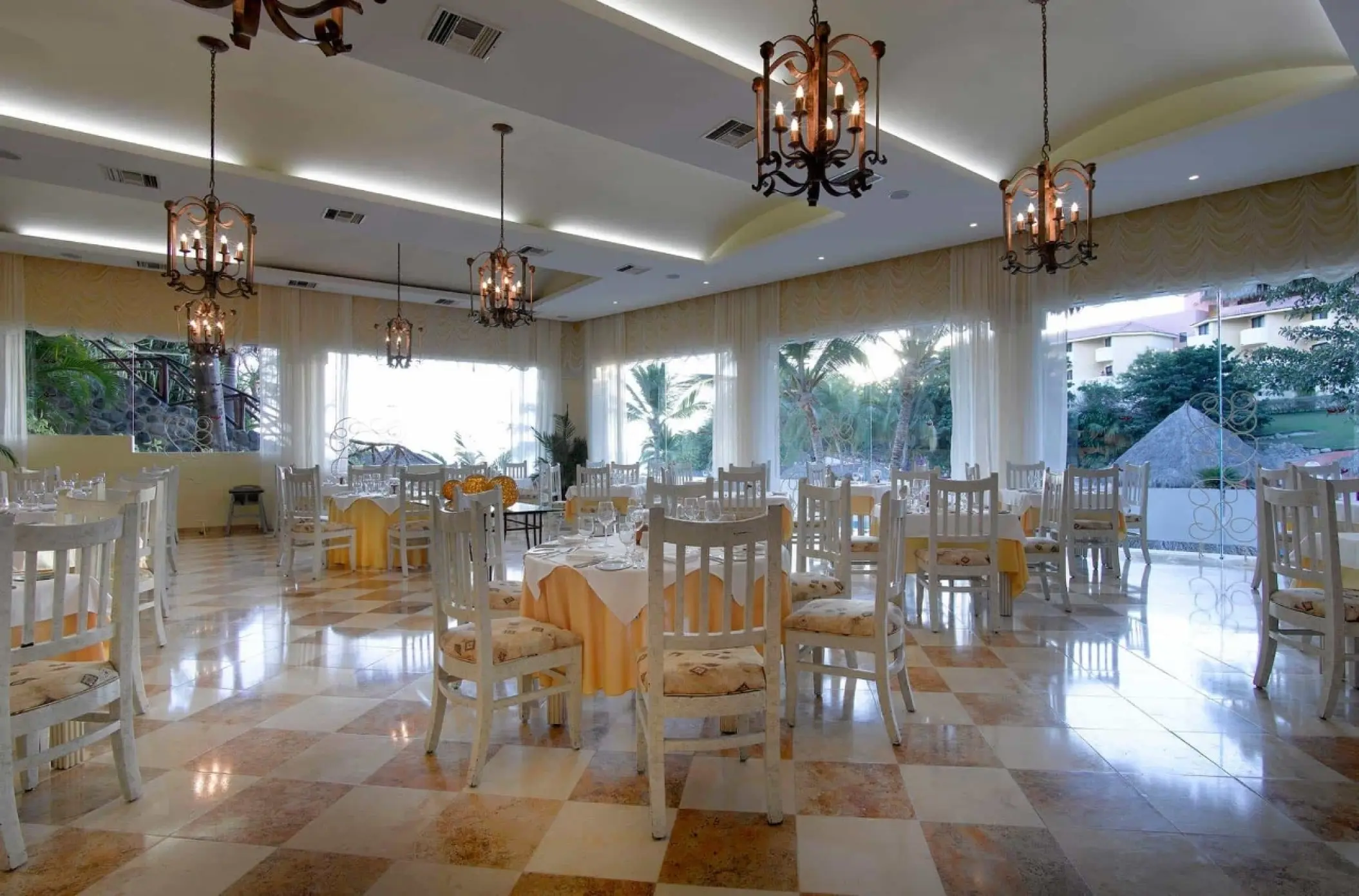 Indoor restaurant with white chairs and chandeliers at Grand Palladium Vallarta, Puerto Vallarta