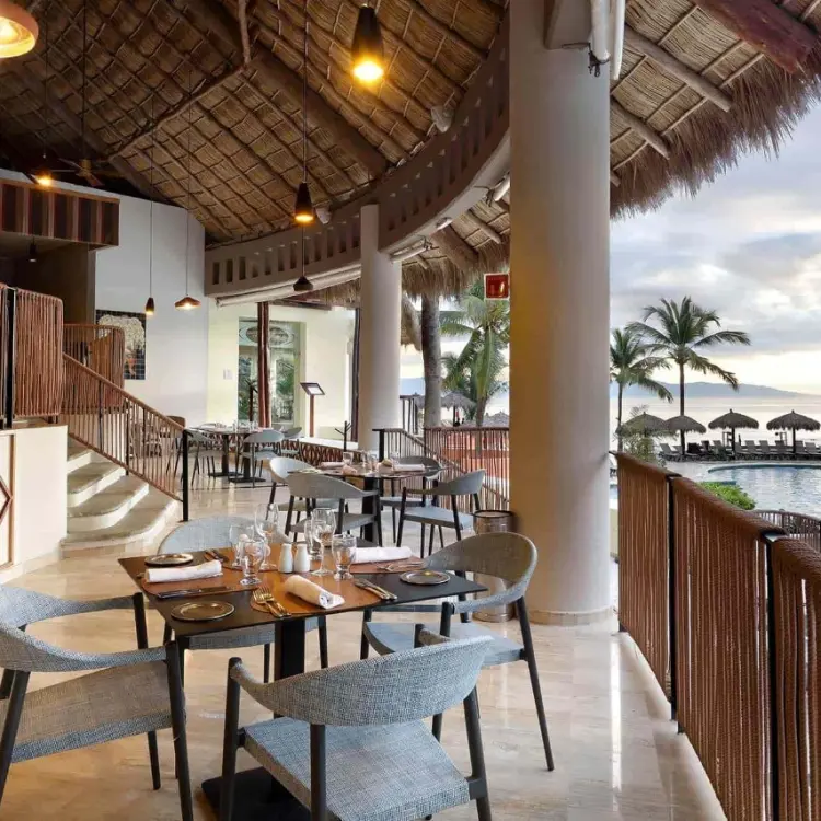 Open-air restaurant with a thatched roof overlooking the pool at Grand Palladium Vallarta, Puerto Vallarta