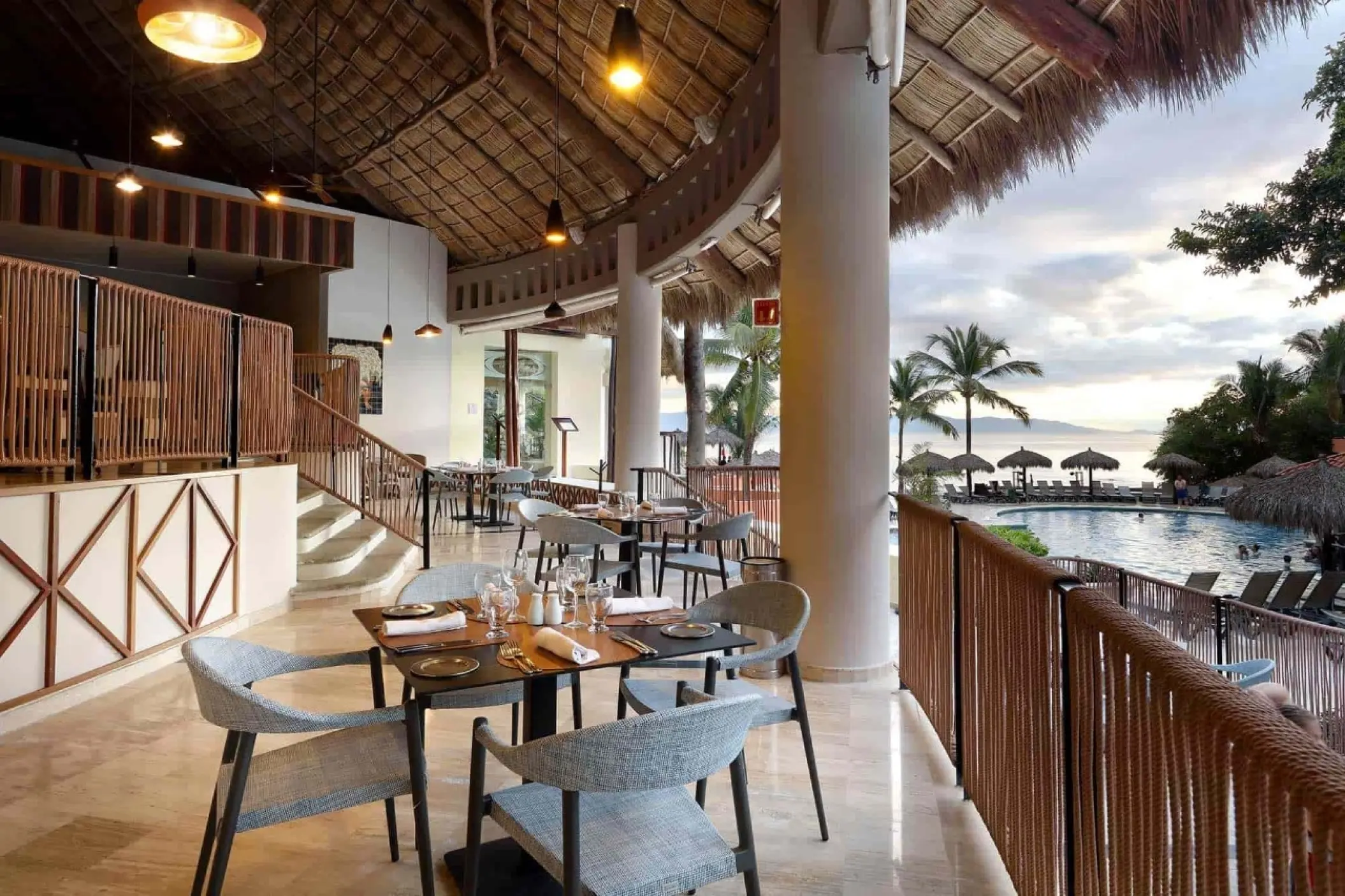 Open-air restaurant with a thatched roof overlooking the pool at Grand Palladium Vallarta, Puerto Vallarta