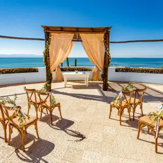 Oceanfront wedding ceremony terrace with a wooden gazebo and cross-back chairs at Grand Palladium Vallarta