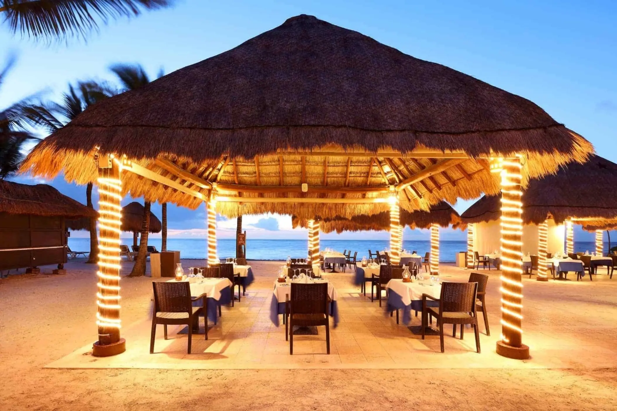 Open-air beachfront restaurant with palapa roofs and fairy lights at Grand Palladium White Sand, Riviera Maya