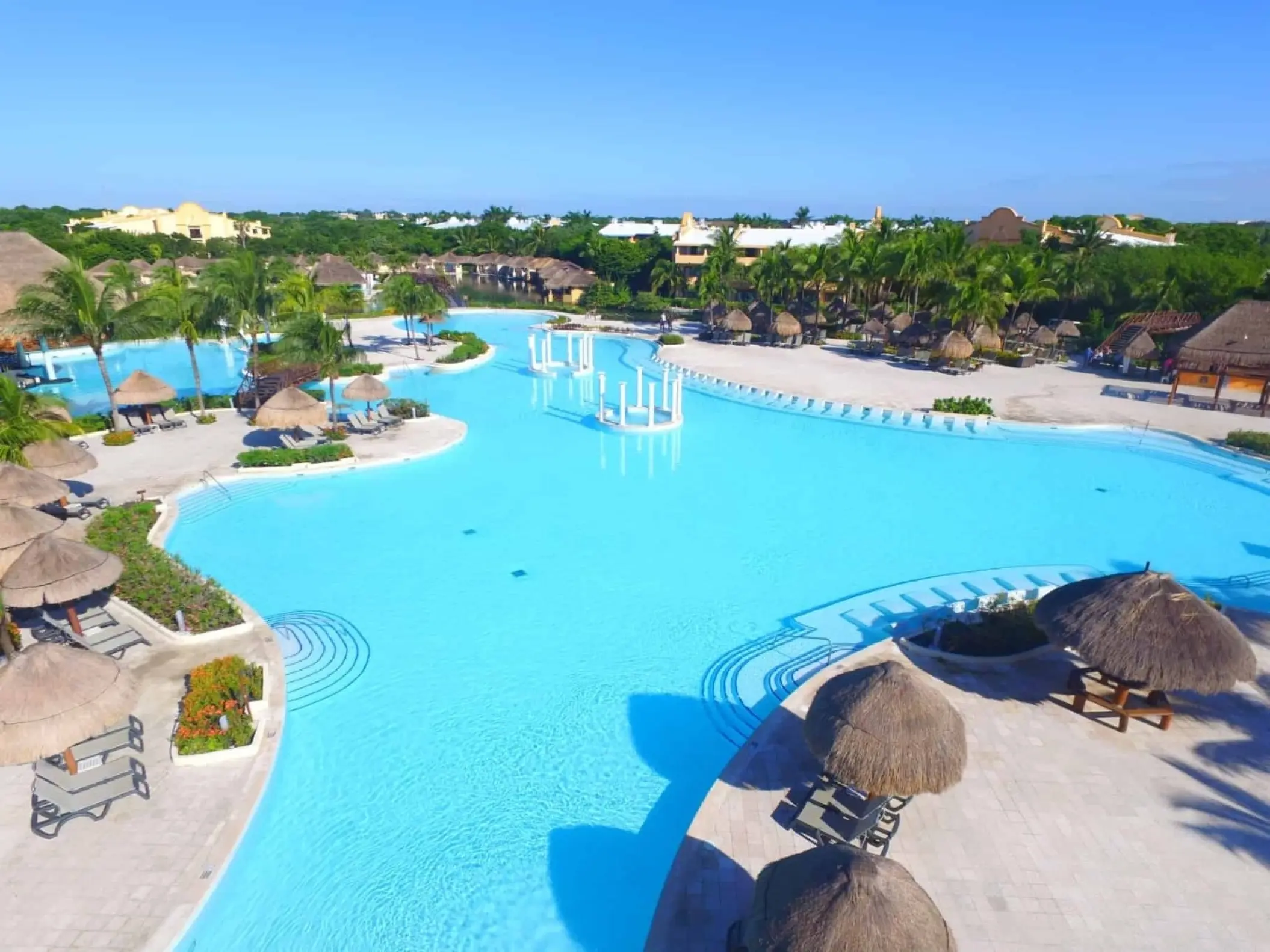 Grand Palladium White Sand swimming pool area with palapas and tropical greenery, Riviera Maya