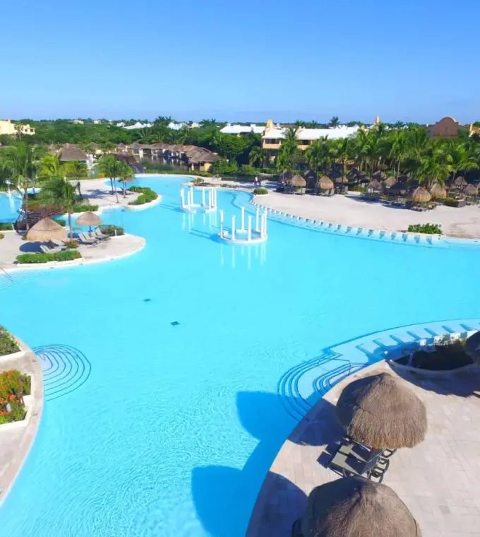 Grand Palladium White Sand swimming pool area with palapas and tropical greenery, Riviera Maya