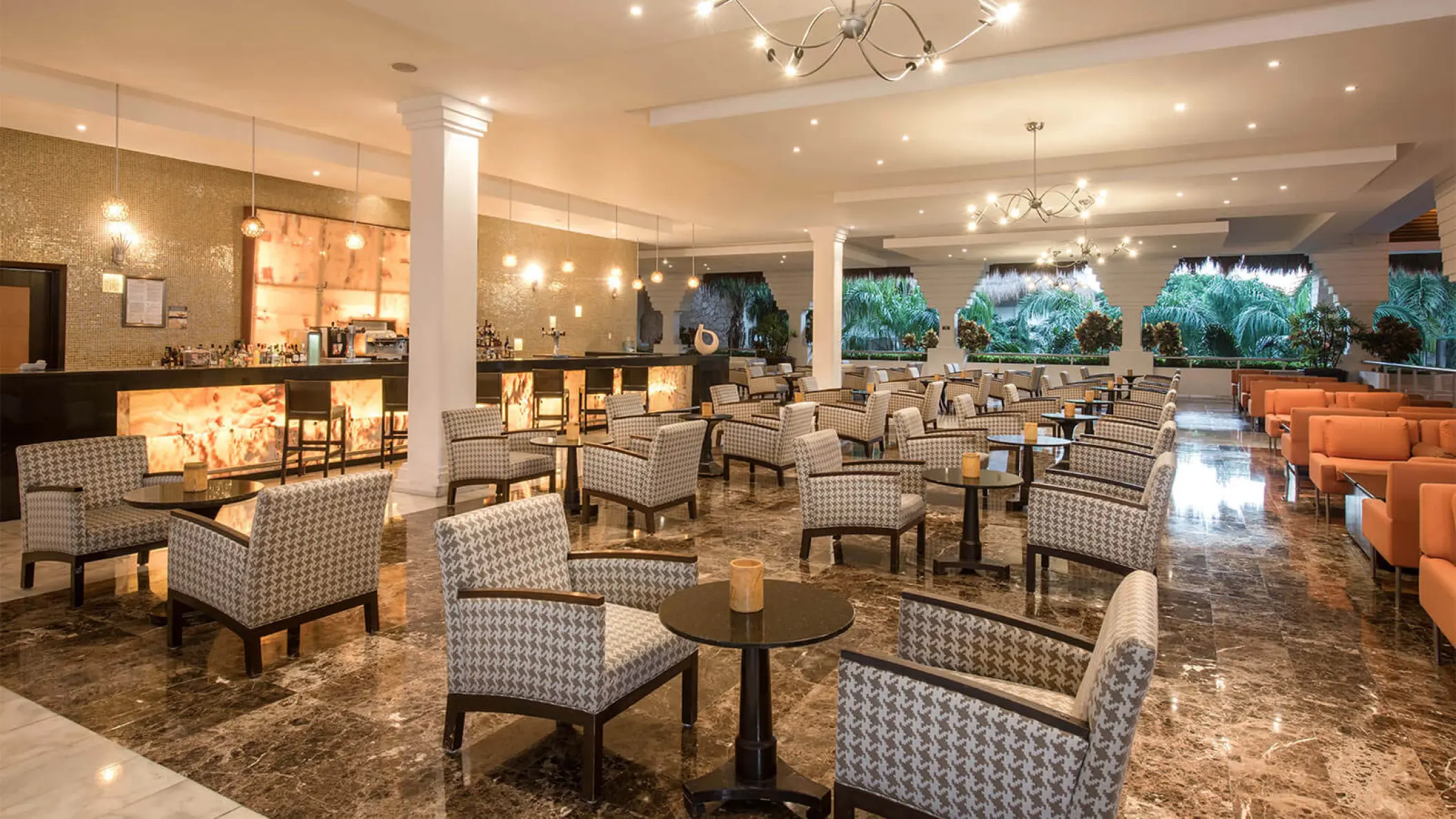 Indoor bar and lounge area with patterned armchairs at Grand Riviera Princess, Playa Del Carmen