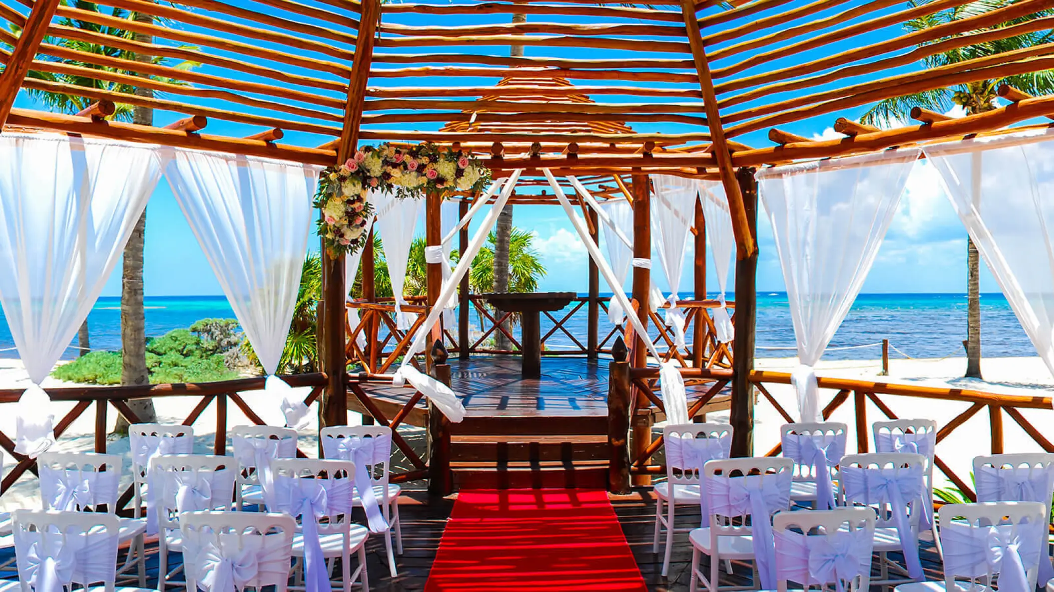 Beachfront wedding ceremony setup with red carpet inside a wooden gazebo at Grand Riviera Princess, Playa Del Carmen