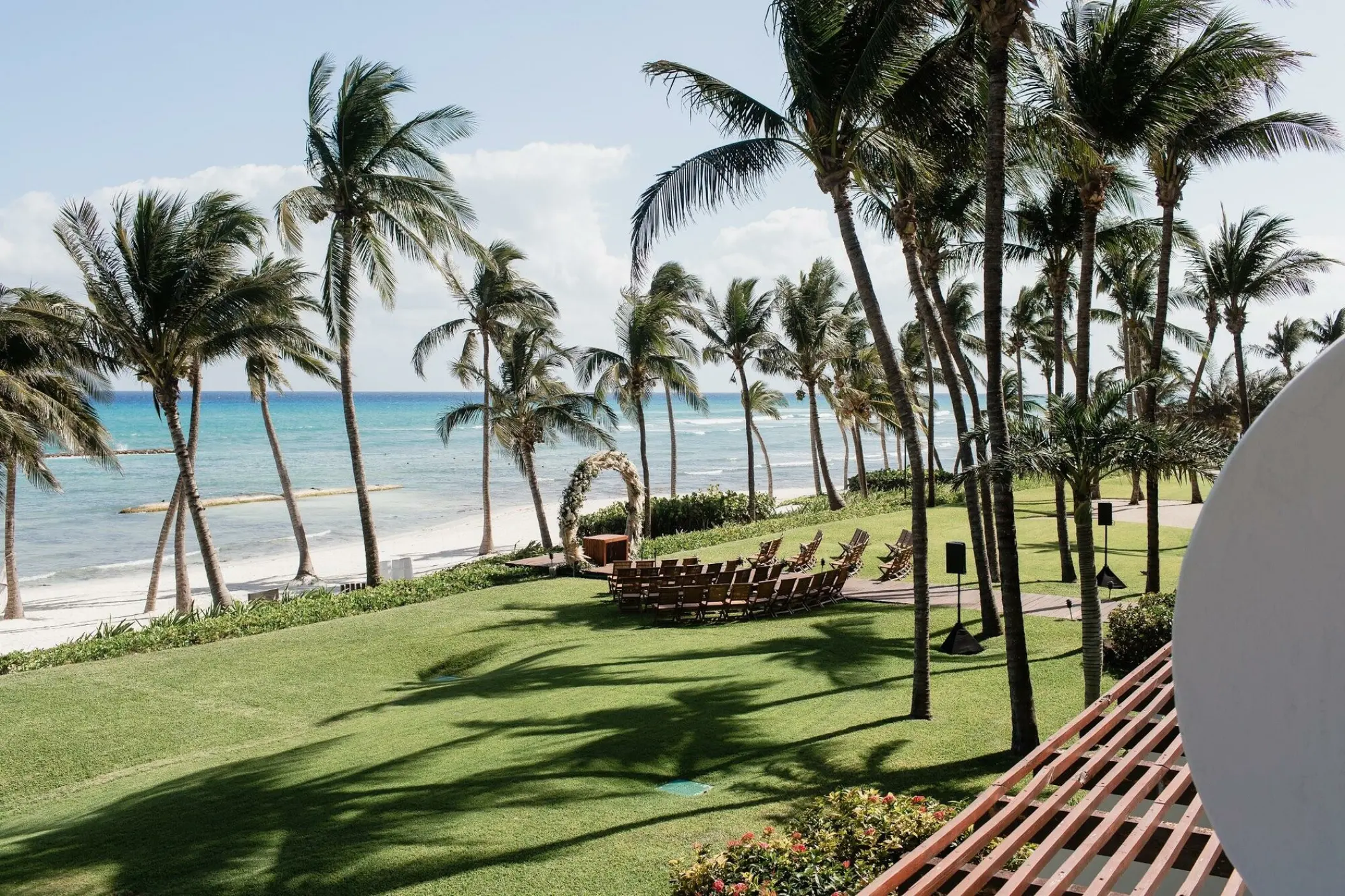 Grassy beach ceremony site with a floral arch and palm trees at Grand Velas Riviera Maya, Riviera Maya