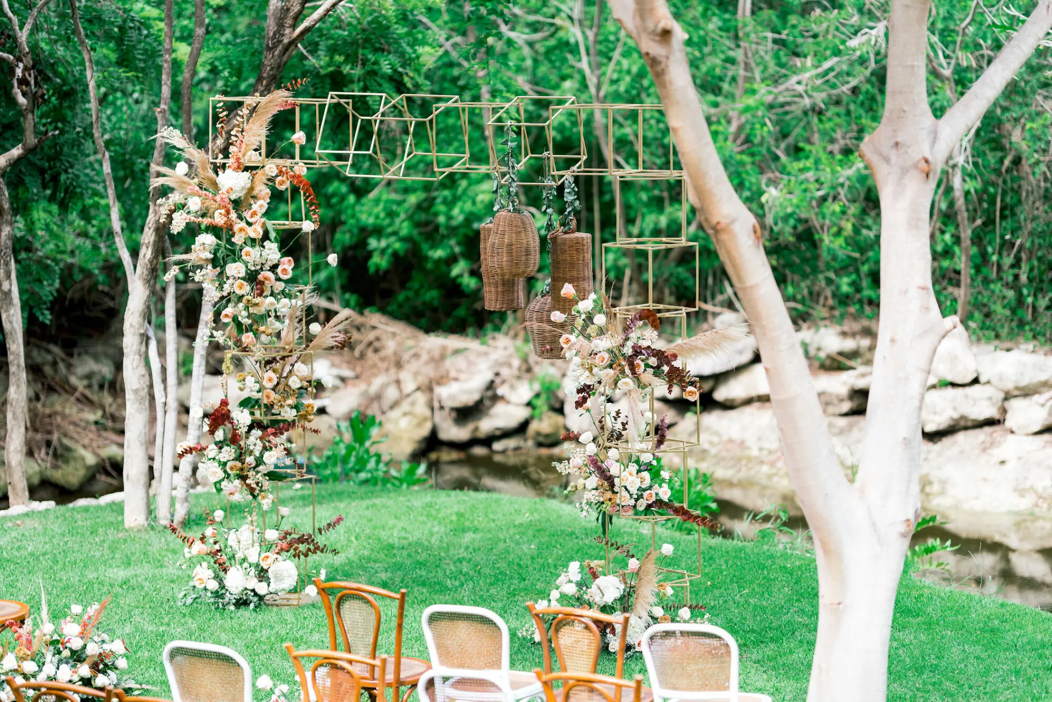 Garden wedding ceremony setup with geometric gold arch at Grand Velas Riviera Maya