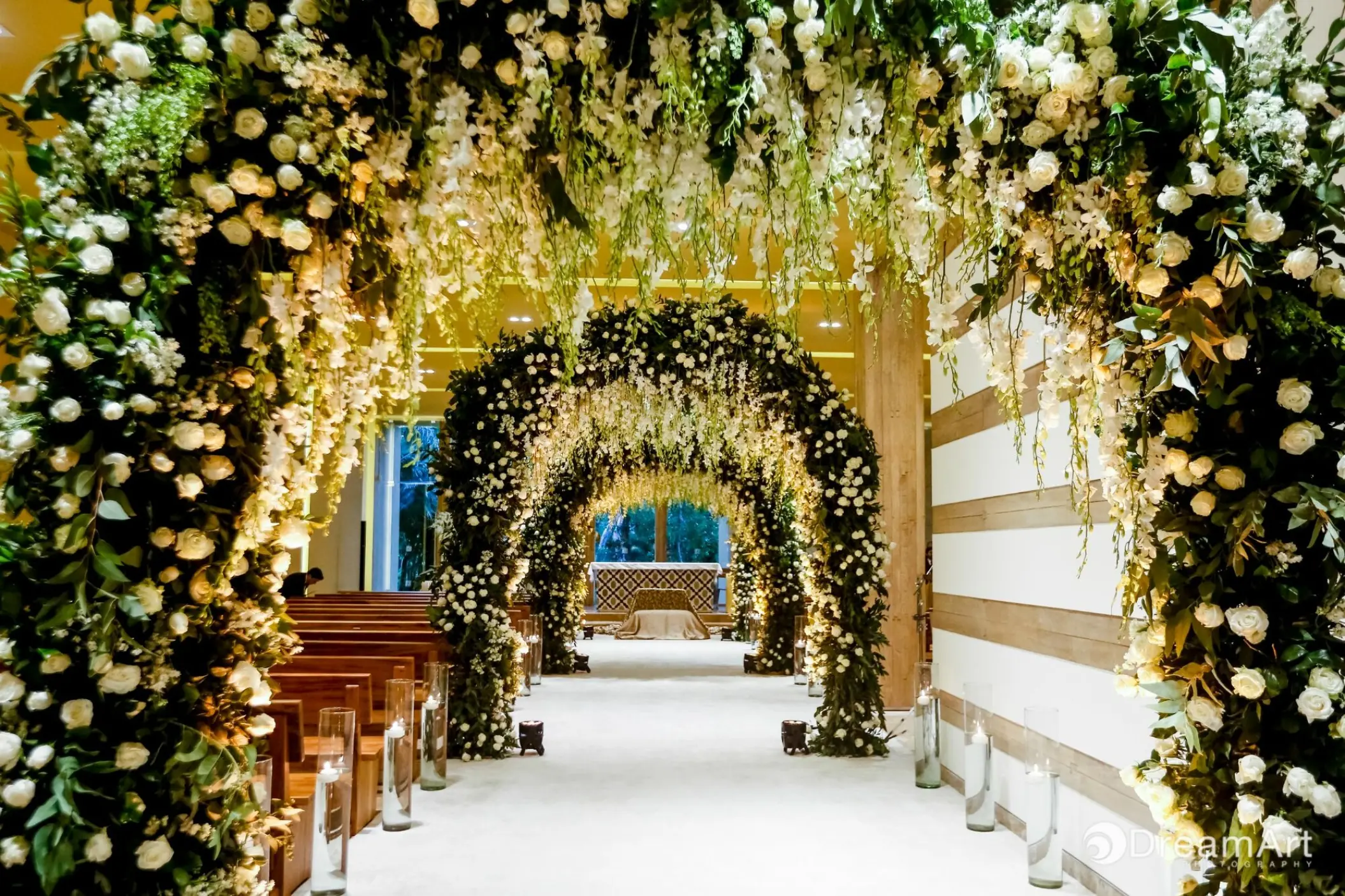 Indoor chapel wedding ceremony aisle with white floral arches at Grand Velas Riviera Maya